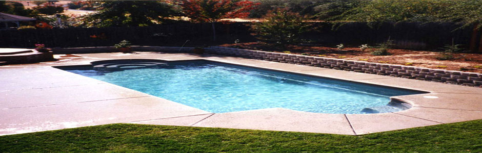 Blue backyard swimming pool framed by lawn and a garden wall